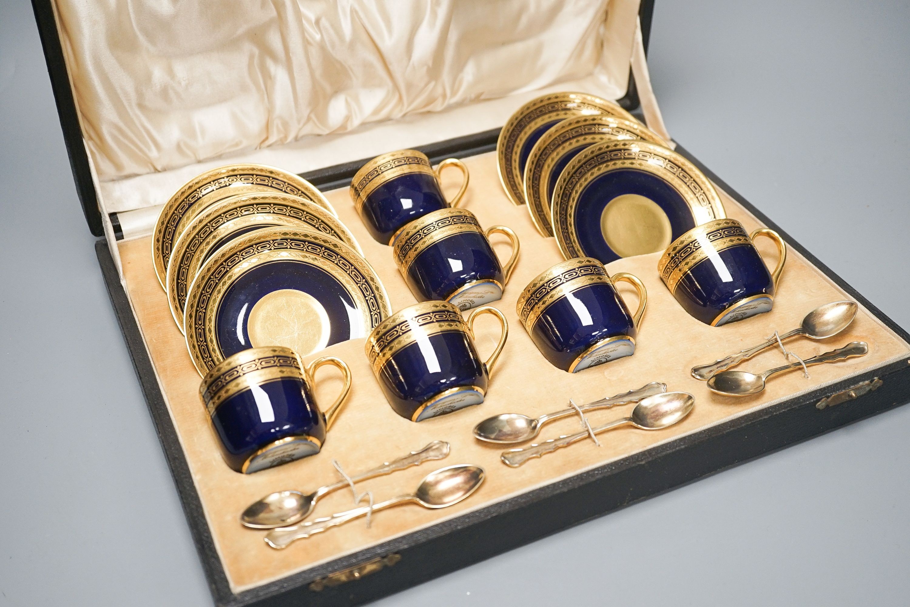 A cased set of six Limoges coffee cups and saucers, six silver gilt spoons